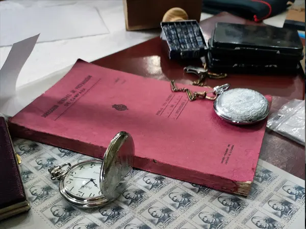 Bodegón de material histórico original de la Guerra Civil Española perteneciente a una exposición. Se aprecian relojes de bolsillo, sellos de la República y un manual de la Dirección General de Instrucción.