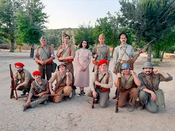 Grupo de recreadores históricos de la Guerra Civil Española de GRH posando en Jaén. Se ven hombres con uniformes republicanos, carlistas y nacionales, armamento de época y una mujer con vestido de civil de la época, en un entorno rural al aire libre.
