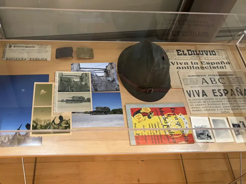 Vitrina con material histórico de la Guerra Civil Española: fotografías originales, recortes de prensa, un casco militar y documentos expuestos en la muestra «50 años de desmemoria» de Jordi Jon.