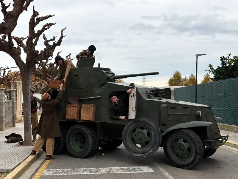 Tanqueta BA-6 con miembros del grupo Frente Andaluz–Divulga Historia circulando por una calle de Flix durante la recreación de la Batalla del Ebro 2025, con varios recreadores cargando cajas sobre el vehículo.