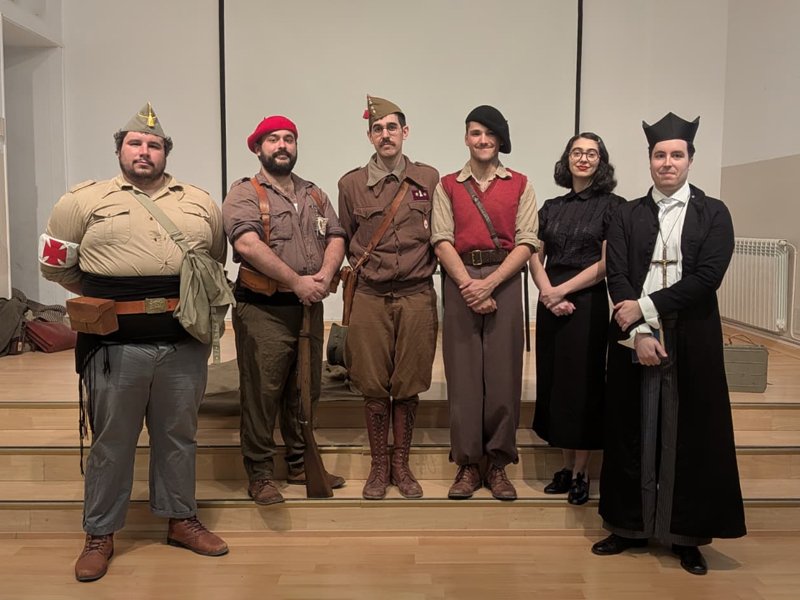 Seis miembros del grupo de recreación histórica El Comité posando con indumentaria de la Guerra Civil Española en el salón de actos del Colegio San José de Calasanz de Barbastro: un camillero republicano, un requeté, un oficial de ingenieros, un miliciano voluntario, una militante del POUM y un profesor escolapio