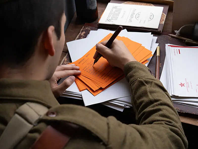 Recreador de El Comité rellenando fichas de alistamiento de la Brigada Mixta en el puesto de propaganda durante la recreación de la batalla del Jarama en Morata de Tajuña 2026.