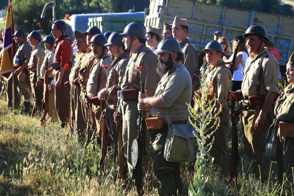 Recreadores en formación con claveles rojos en un homenaje a soldados no identificados hallados en una fosa común de la Guerra Civil española