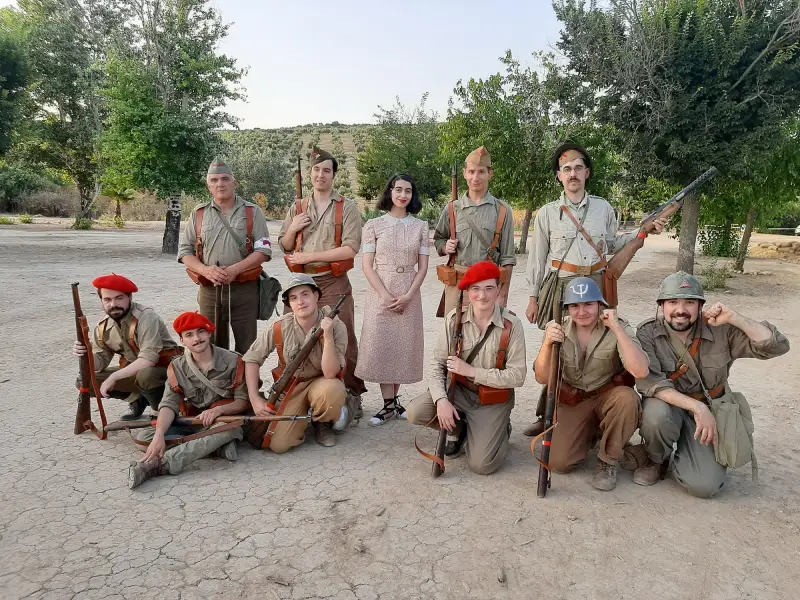Grupo de recreadores caracterizados como milicianos republicanos de 1936 junto a una recreadora con vestido civil de época